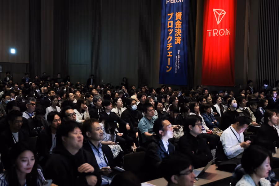 暗い会議室で熱心に講演を聞く多数の参加者たち。